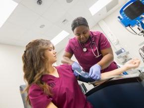 Two nursing students practice with a blood pressure cuff